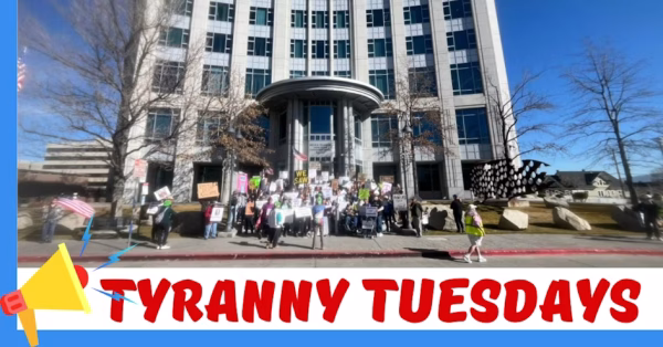 Group of people with signs standing in front of a building Tyranny Tuesday